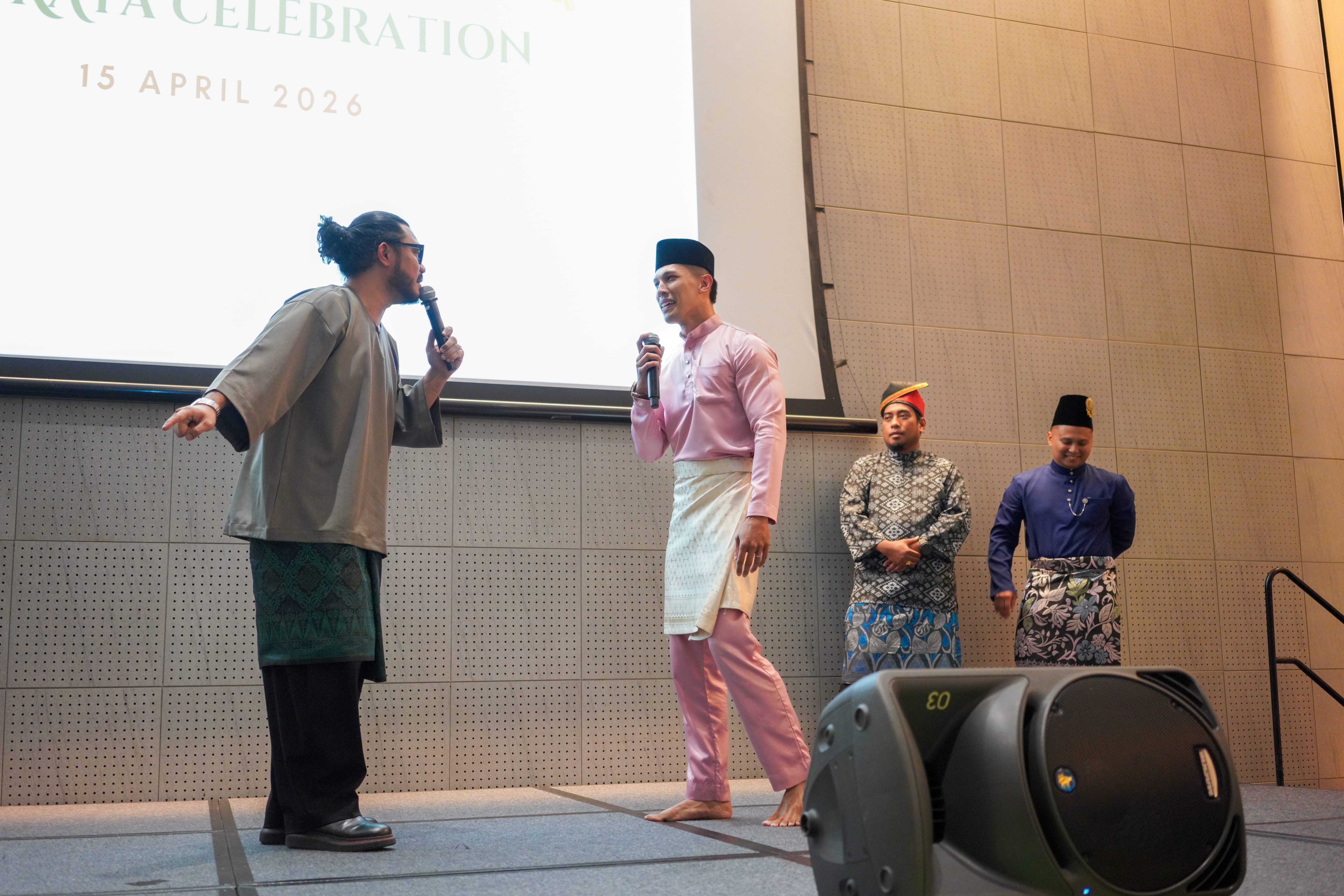 Two performers acting out a comedic scene on stage with microphones as supporting performers wait behind them.